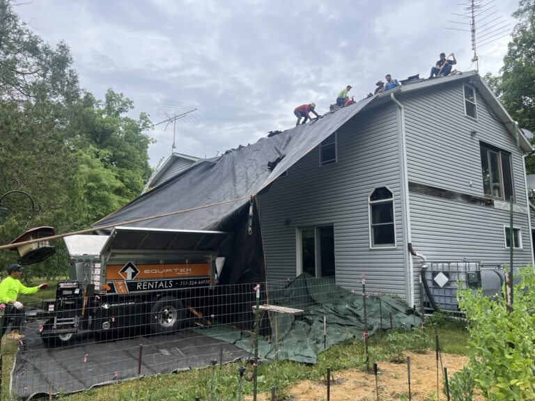 gray house with tarp and roofer buggy parked out front