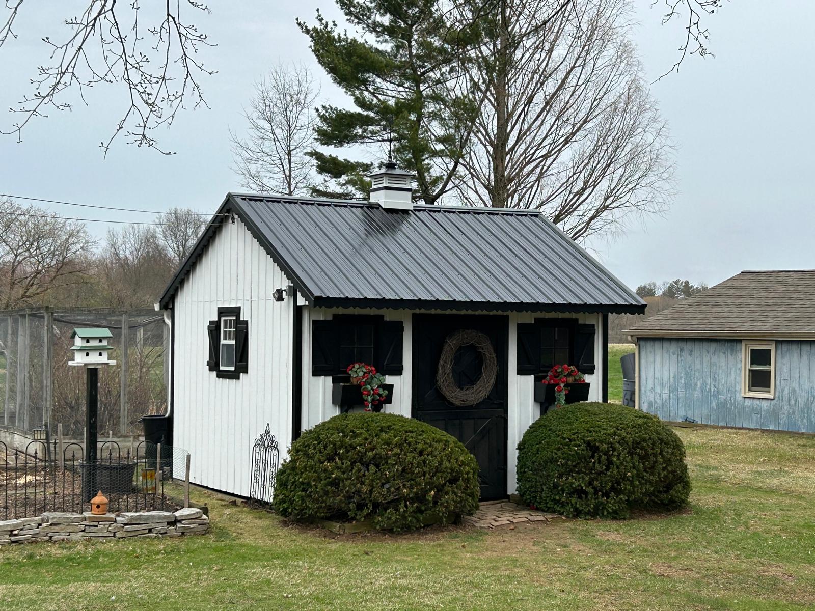 white shed with a newly installed black metal roof