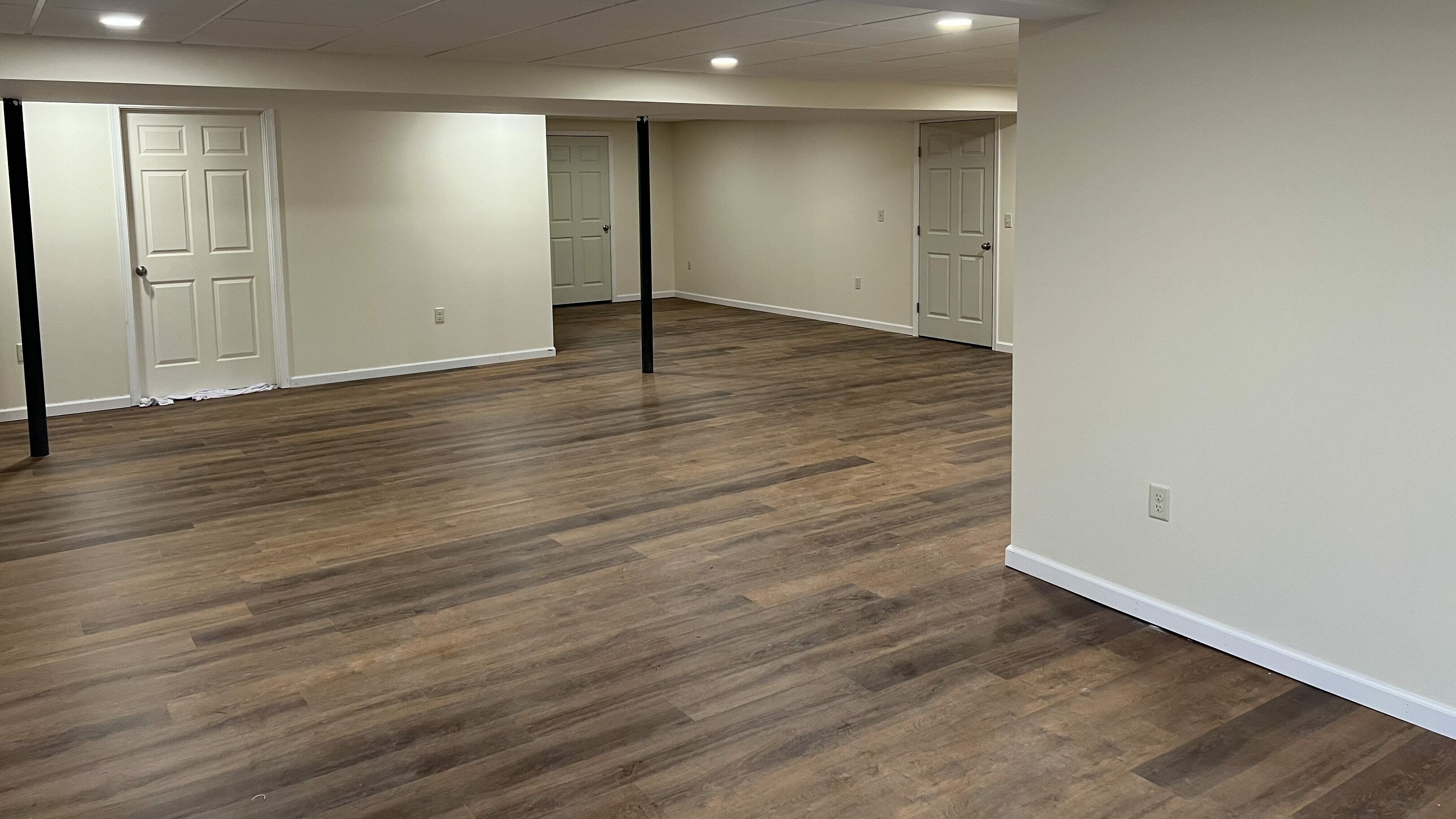 cream colored basement with wood flooring and two black banisters in Denver PA