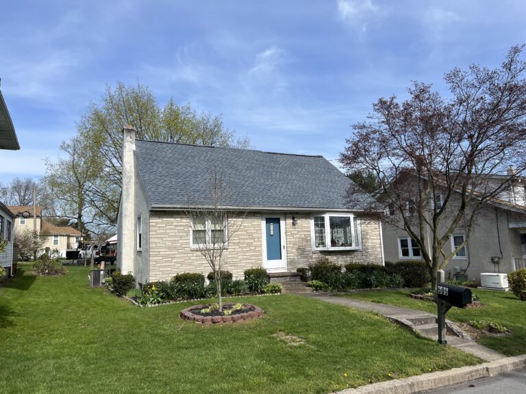 cream colored stone home with blue front door and new asphalt shingle roof