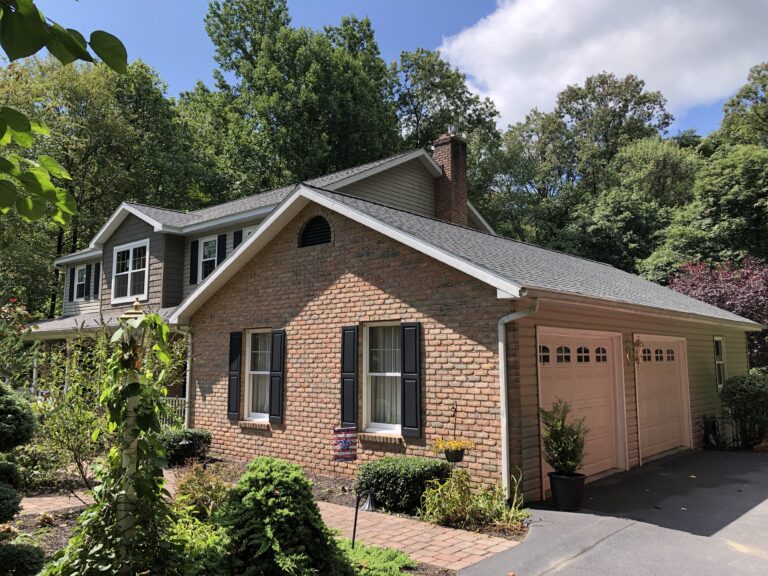 red stone home with gray and navy blue siding with a new asphalt shingle roof