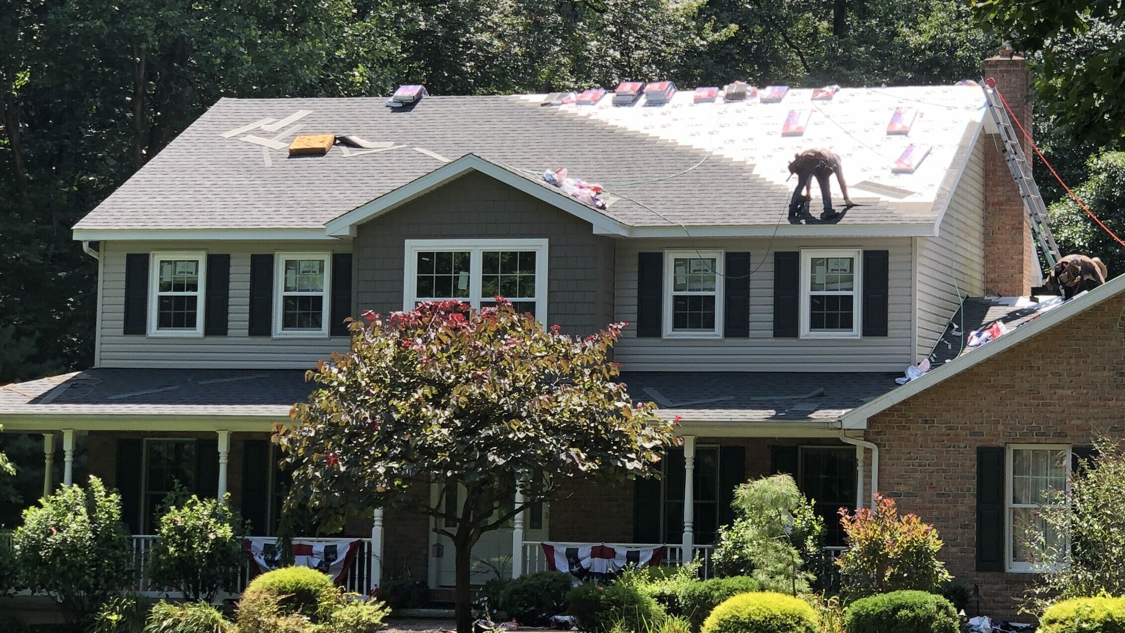 residential roofing contractor in Manheim PA on top of roof of a gray and blue home with red stones